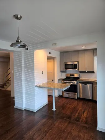 a kitchen with stainless steel appliances kitchen island granite countertop a stove a refrigerator and a wooden floors