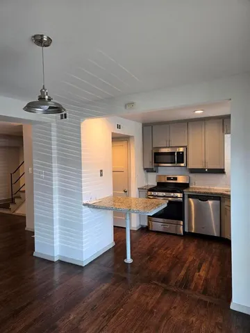 a kitchen with stainless steel appliances kitchen island granite countertop a stove a refrigerator and a wooden floors