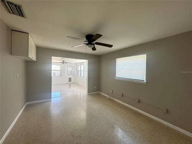 a view of empty room with wooden floor and fan