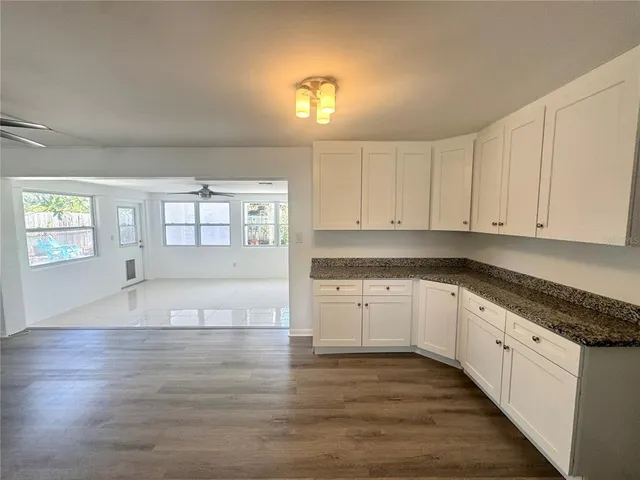 a open kitchen with granite countertop white cabinets and wooden floor