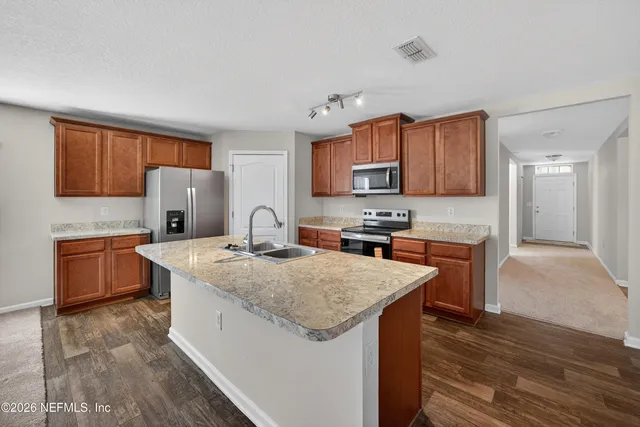 a kitchen with stainless steel appliances granite countertop a stove a sink dishwasher and a refrigerator with wooden floor