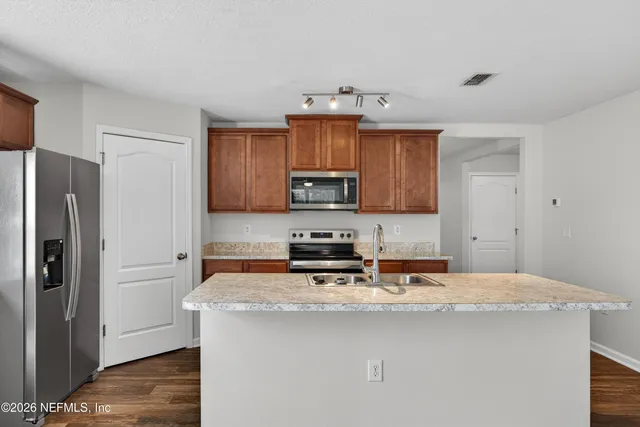 a kitchen with granite countertop a refrigerator stove and microwave