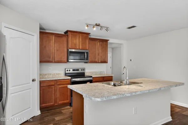 a kitchen with granite countertop a sink cabinets stainless steel appliances and a counter top space