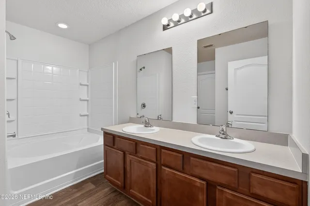 a bathroom with a sink double vanity granite tub shower and a mirror