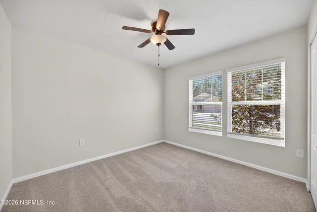 an empty room with windows and fan
