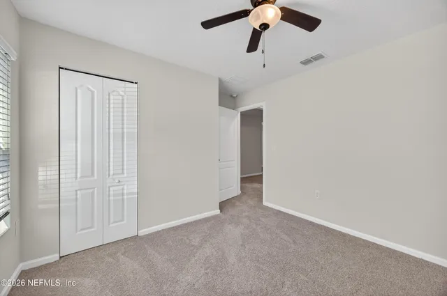 an empty room with a ceiling fan and carpet