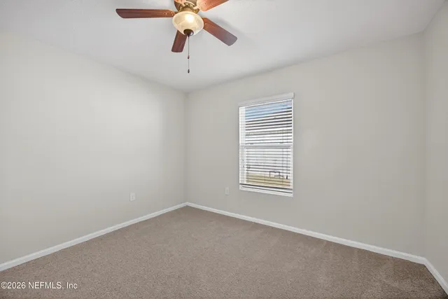 an empty room with a window and a fan