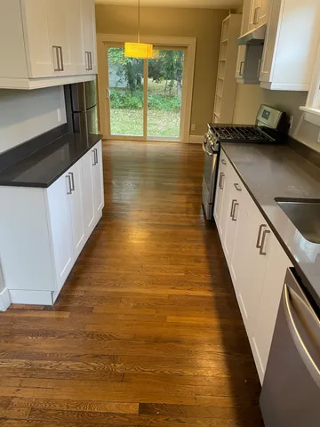 a kitchen with granite countertop a stove a sink and a refrigerator