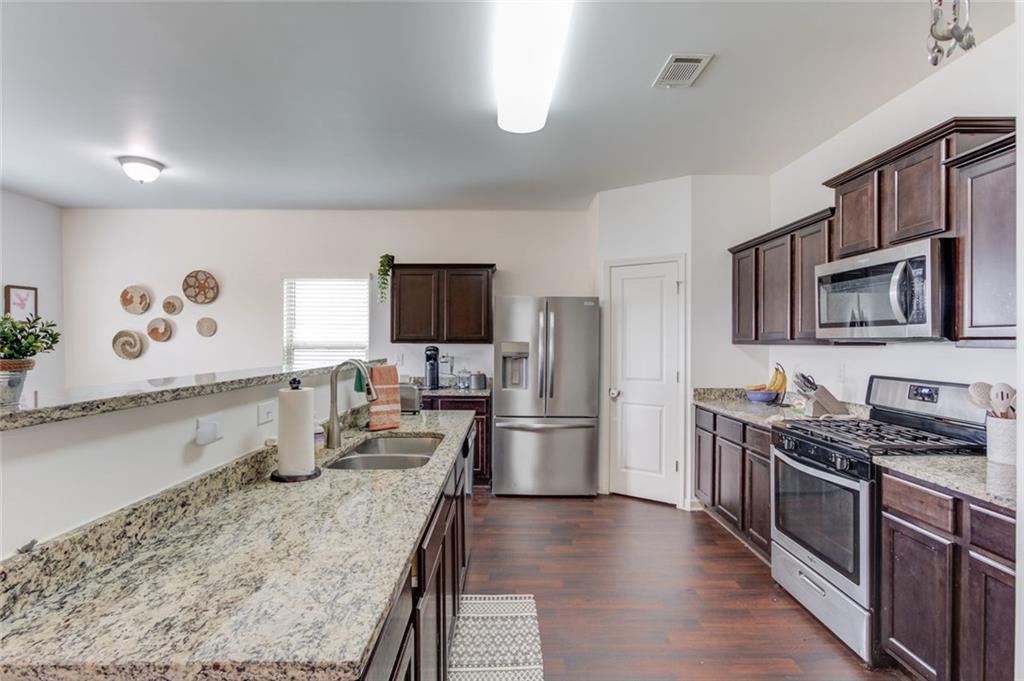331 Merigold Way Pendergrass, GA 30567 - Photo 10 of 39 a kitchen with stainless steel appliances granite countertop a stove top oven a sink dishwasher a refrigerator and a dining table with wooden floor