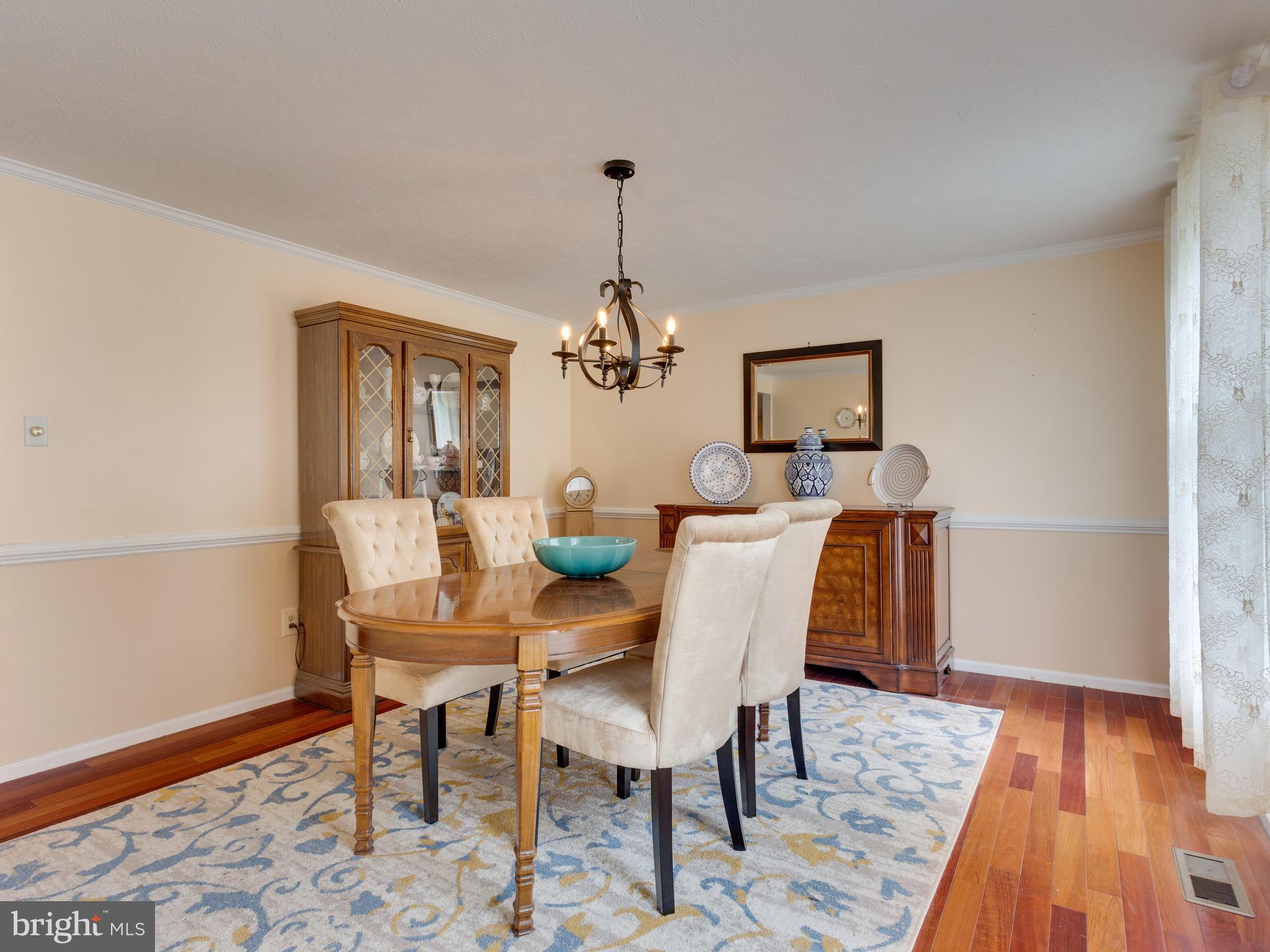 7817 Roundabout Way Springfield, VA 22153 - Photo 5 of 30 a dining room with furniture wooden floor a rug and a chandelier