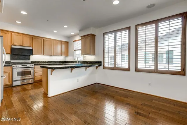 a kitchen with stainless steel appliances granite countertop a refrigerator a stove a sink and a microwave