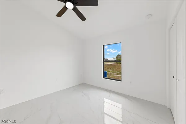 an empty room with a window and a ceiling fan