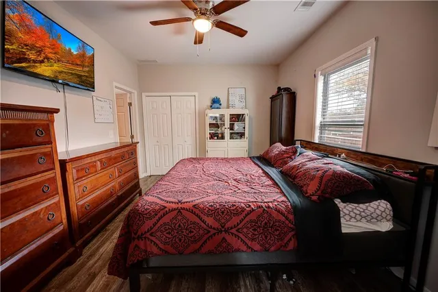 a bedroom with a bed and dresser with wooden floor