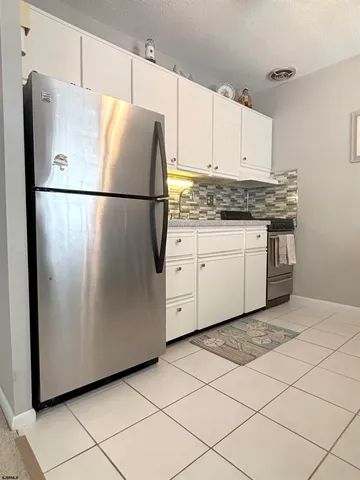 a kitchen with white cabinets and refrigerator