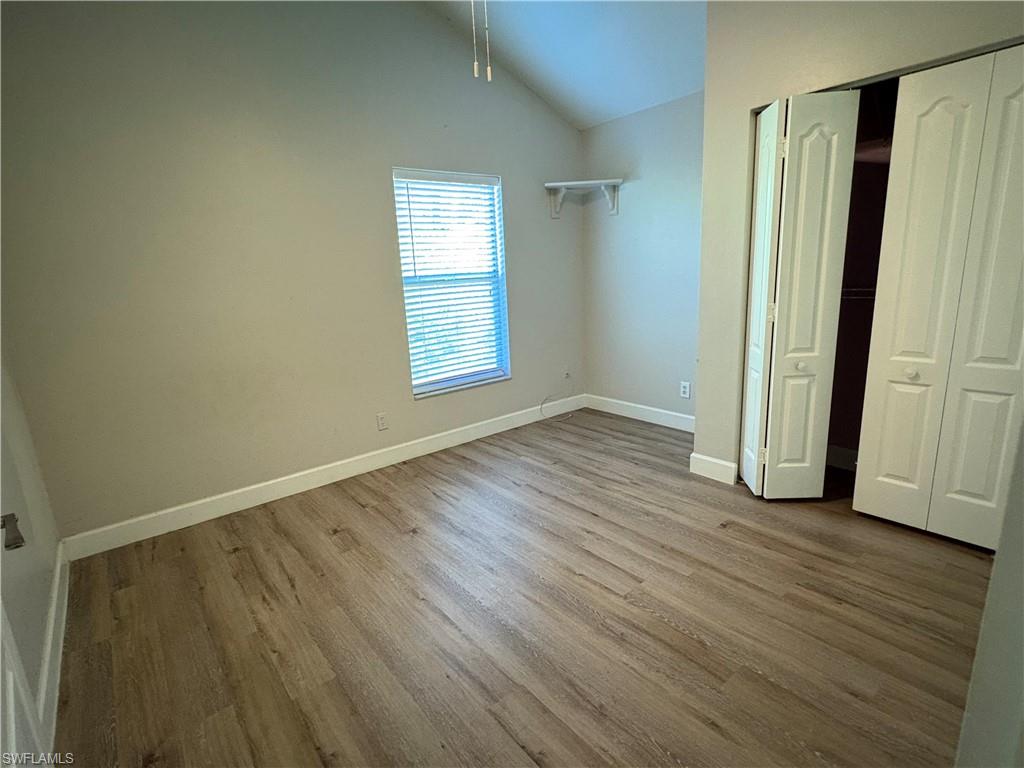 804 Bluebird Street Naples, FL 34104 - Photo 23 of 42 Unfurnished bedroom with wood finished floors, vaulted ceiling, and a closet