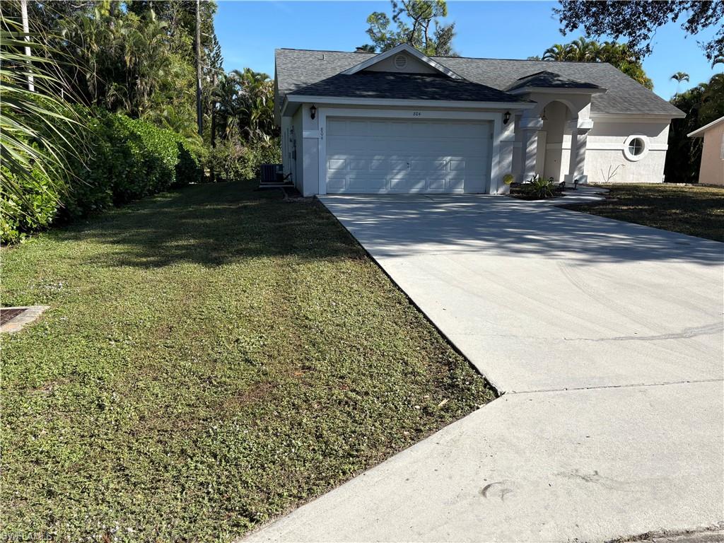 804 Bluebird Street Naples, FL 34104 - Photo 28 of 42 View of front of house with concrete driveway, a front lawn, a garage, and a shingled roof