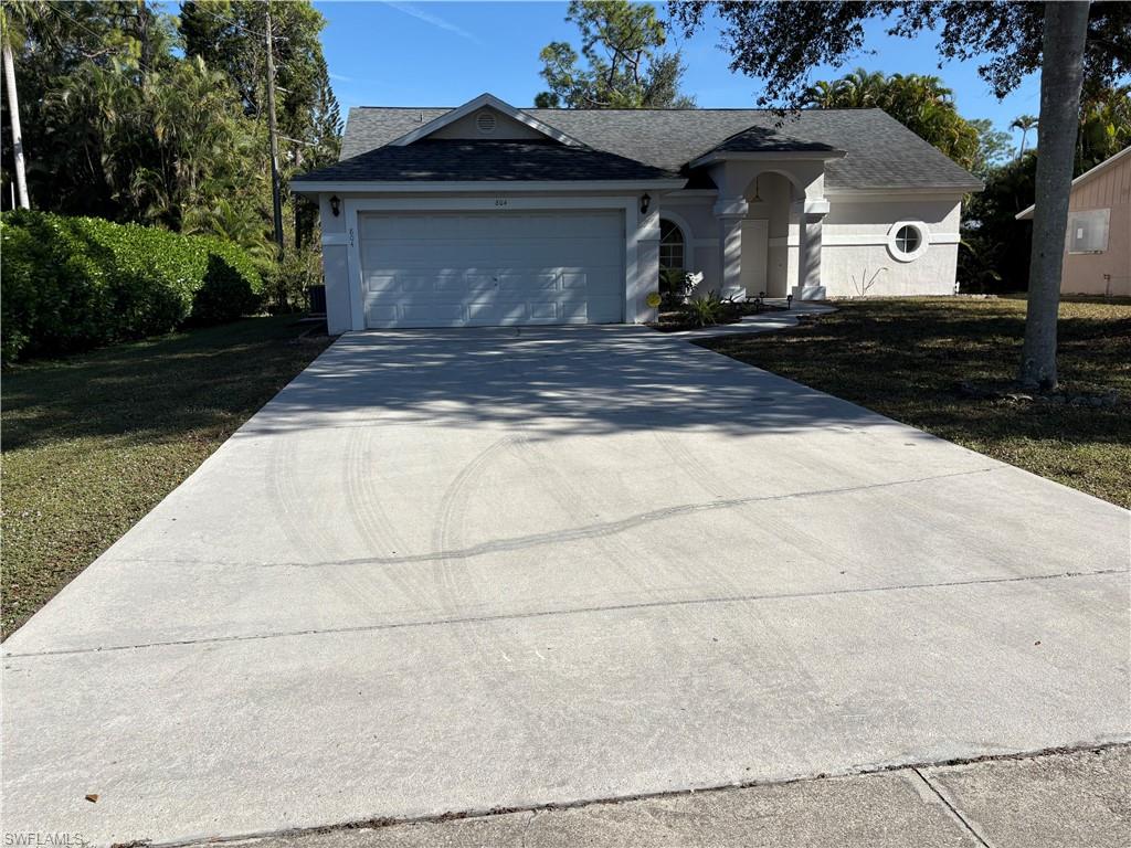 804 Bluebird Street Naples, FL 34104 - Photo 30 of 42 Ranch-style home with concrete driveway, roof with shingles, an attached garage, and a front lawn