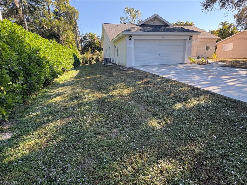 804 Bluebird Street Naples, FL 34104 - Photo 36 of 42 View of home's exterior featuring driveway, stucco siding, a yard, and a garage