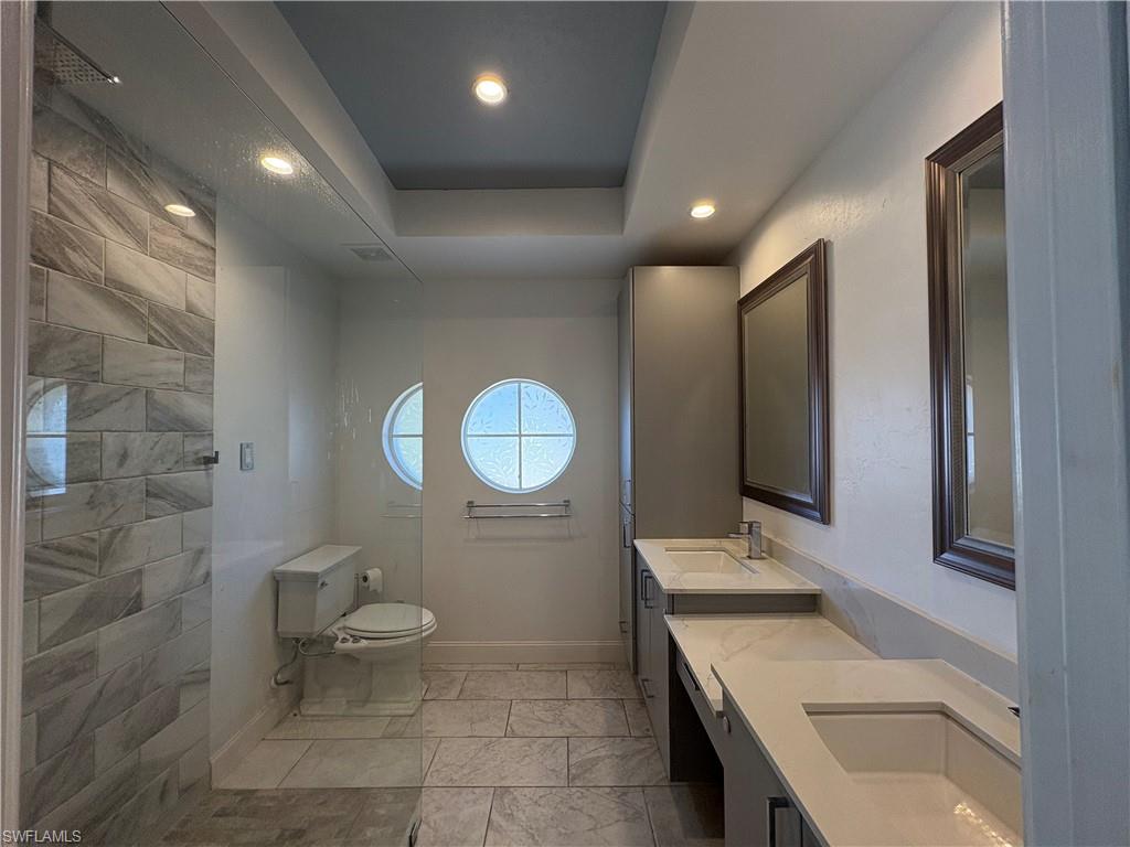 804 Bluebird Street Naples, FL 34104 - Photo 38 of 42 Bathroom with a tray ceiling, double vanity, recessed lighting, and a walk in shower
