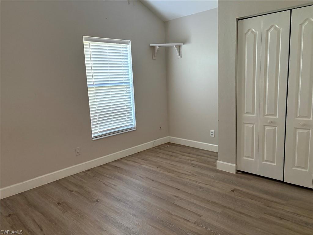 804 Bluebird Street Naples, FL 34104 - Photo 39 of 42 Unfurnished bedroom featuring lofted ceiling, light wood-type flooring, and a closet