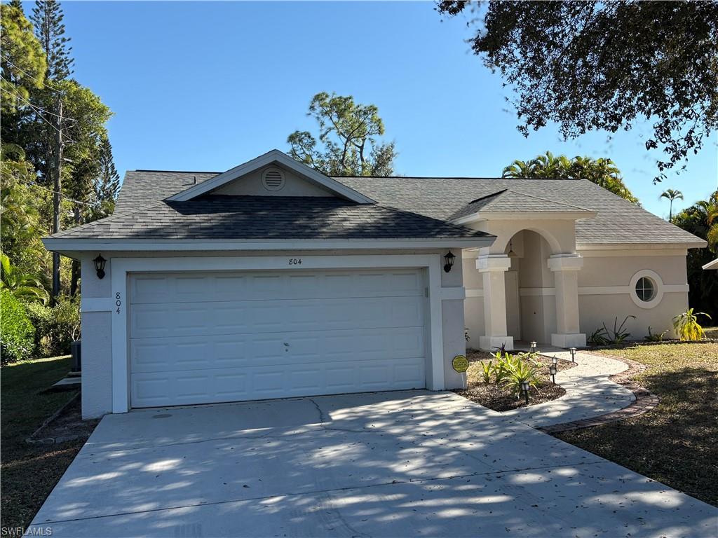 804 Bluebird Street Naples, FL 34104 - Photo 41 of 42 Single story home featuring a shingled roof, driveway, stucco siding, and a garage