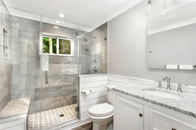a bathroom with a granite countertop sink a toilet and shower