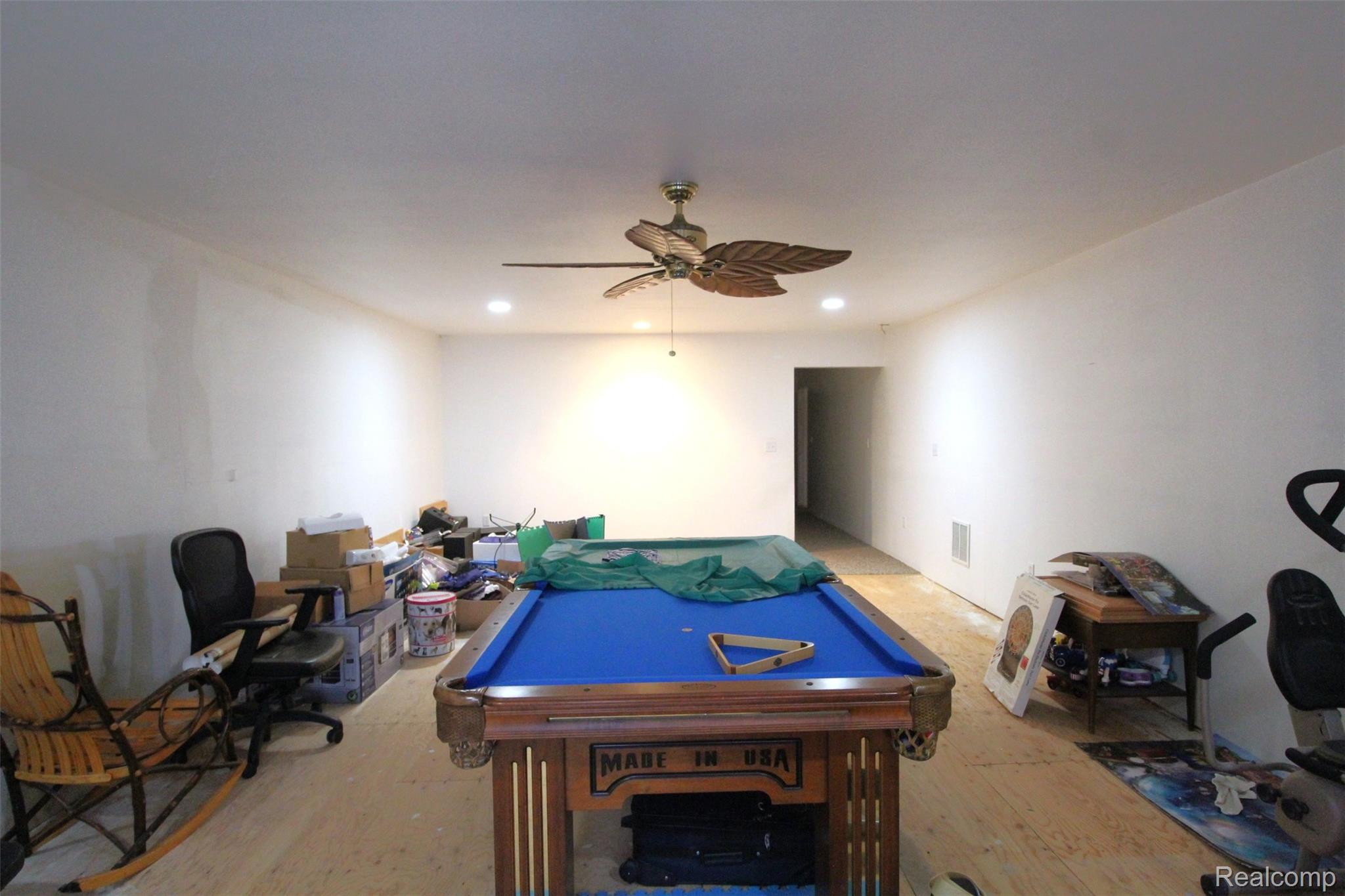 2568 Valentine Road Lapeer, MI 48446 - Photo 18 of 42 Spacious recreation room featuring a full-size pool table with blue felt, wood-finish flooring throughout, ceiling fan with integrated lighting, and ample square footage ideal for entertainment and leisure activities