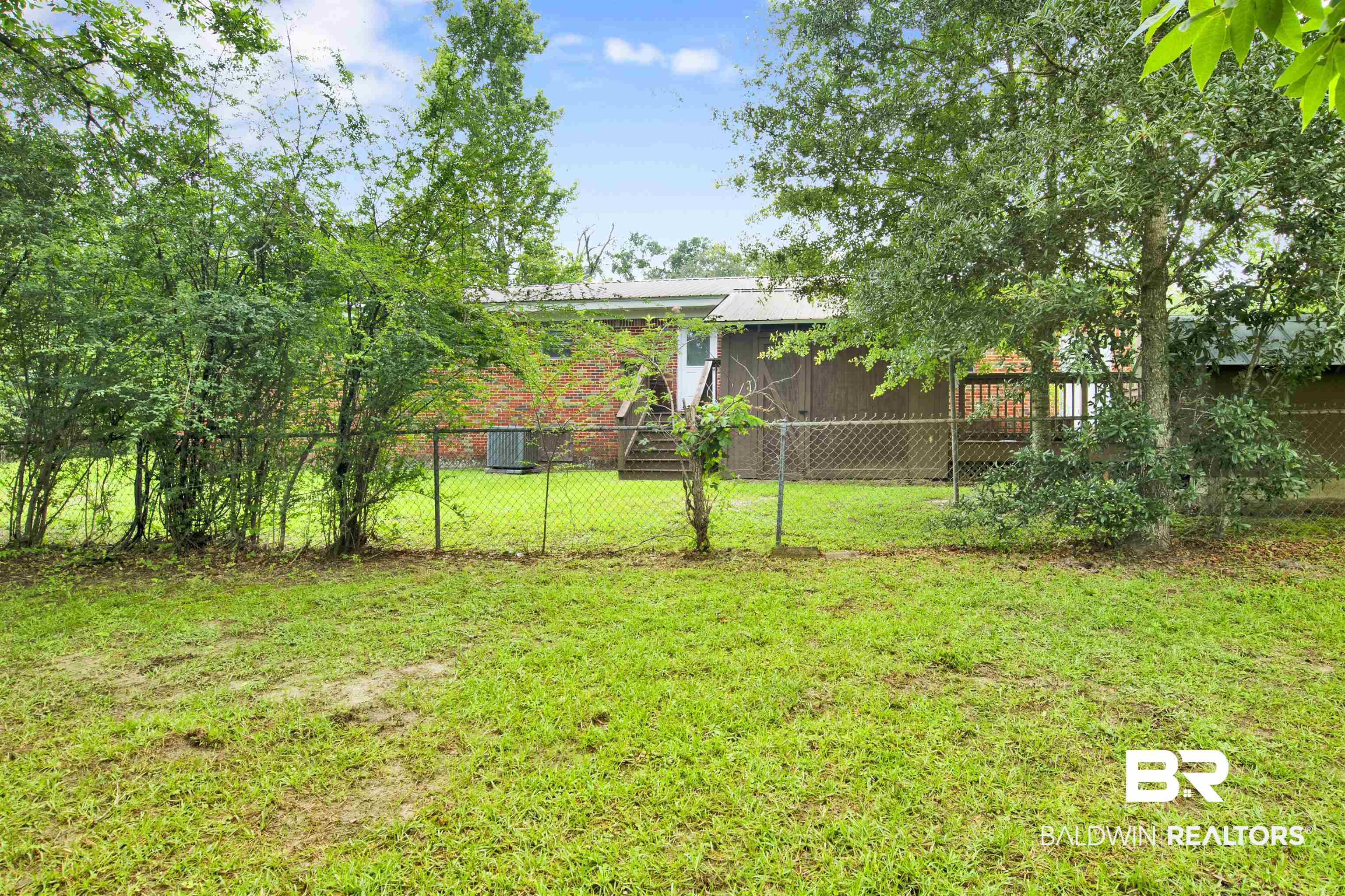 17714 Horseneck Road Bay Minette, AL 36507 - Photo 35 of 36 Expansive backyard featuring a chain-link fence, mature trees, and a wooden deck
