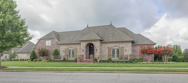 a front view of a house with a garden and trees