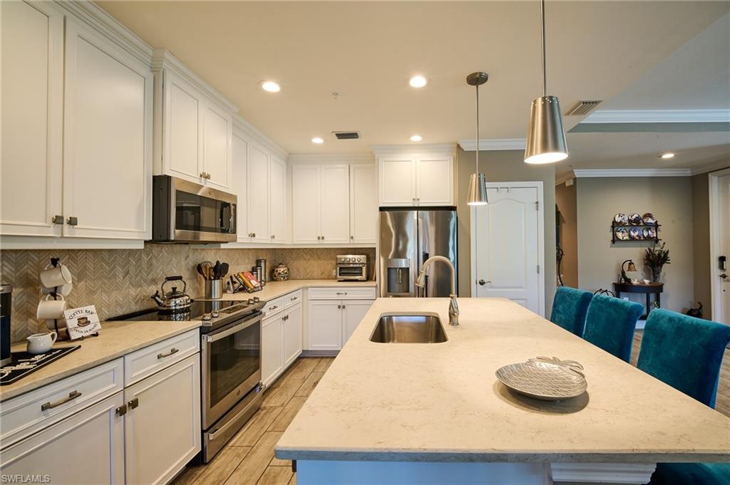 2319 Sawyers Hill Road, Unit 701 Naples, FL 34120 - Photo 6 of 36 a kitchen with stainless steel appliances granite countertop a sink a stove a refrigerator a microwave oven with cabinets and wooden floor
