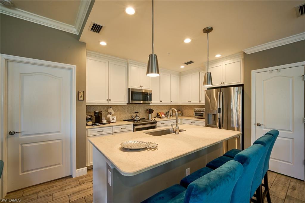 2319 Sawyers Hill Road, Unit 701 Naples, FL 34120 - Photo 8 of 36 a kitchen with refrigerator and white cabinets