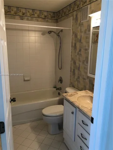 a bathroom with a granite countertop bathtub shower sink vanity and toilet