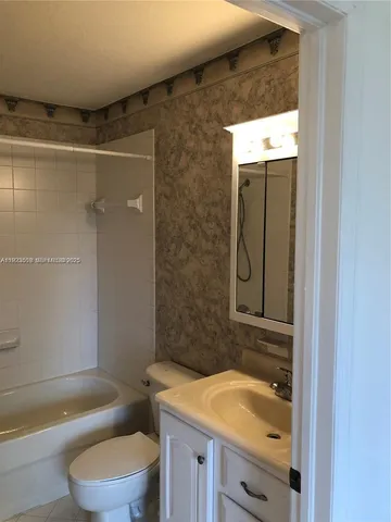 a bathroom with a granite countertop bathtub shower sink mirror and toilet