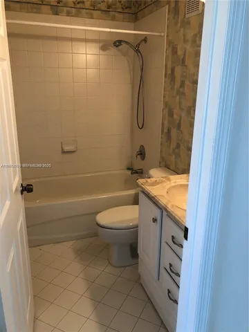 a bathroom with a granite countertop bathtub shower sink vanity and toilet