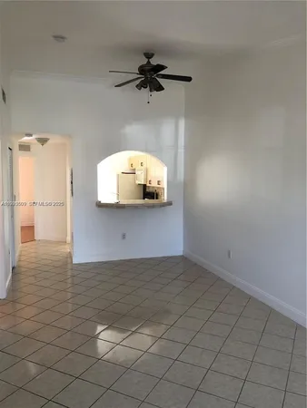 an empty room with a chandelier fan and windows