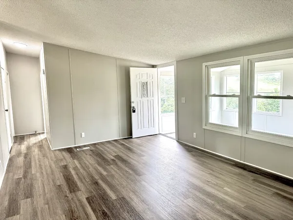 a view of an empty room with wooden floor and a window