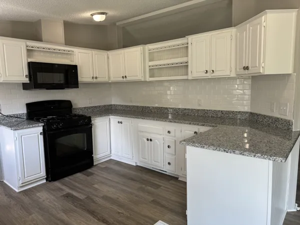 a kitchen with granite countertop white cabinets and black appliances