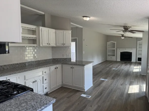 a kitchen with granite countertop a stove top oven a sink dishwasher and a fireplace with wooden floor