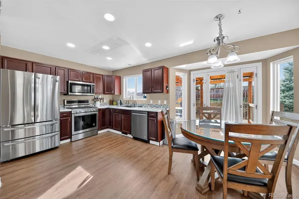 a kitchen with stainless steel appliances kitchen island granite countertop a table chairs stove and refrigerator