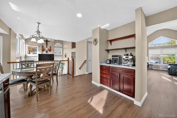a open kitchen with stainless steel appliances granite countertop a refrigerator a stove top oven a dining table and chairs with wooden floor