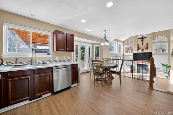 a open kitchen with stainless steel appliances granite countertop a stove top oven a sink dishwasher a dining table and chairs with wooden floor