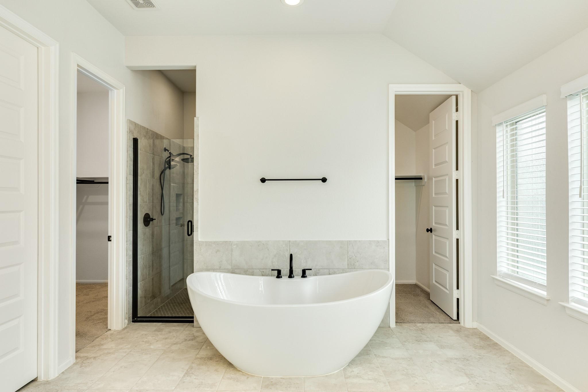 10115 Stride Court Rosharon, TX 77583 - Photo 15 of 40 The primary bathroom serves as a private, luxurious sanctuary, anchored by an astonishing deep-soaking tub and a sophisticated, modern walk-in glass shower. Designed for both functionality and elegance, the suite includes exceptionally spacious double closets that offer extensive room for wardrobe organization and storage. Every detail, from the high-end hardware to the thoughtful layout, contributes to a tranquil, spa-like atmosphere that seamlessly blends comfort with a refined, contemporary aesthetic.