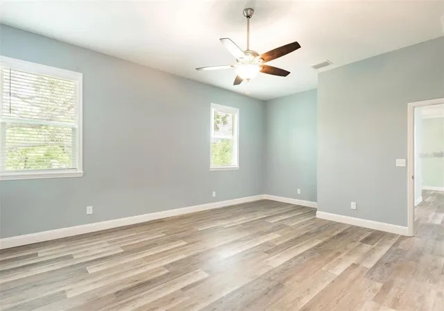 a view of an empty room with window and chandelier fan