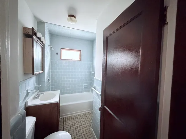 a bathroom with a bathtub sink vanity mirror and toilet