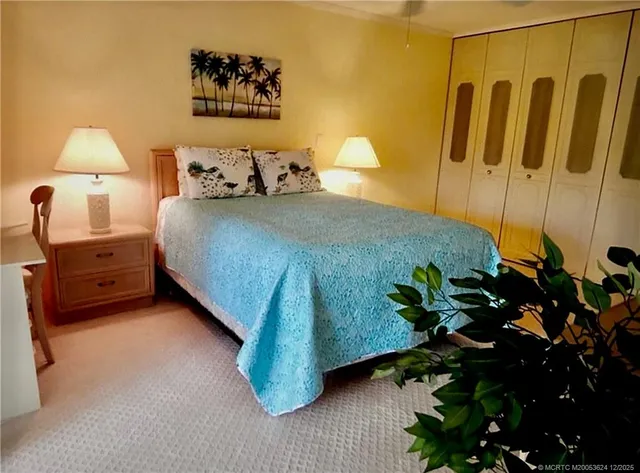 a bedroom with a bed dresser and a potted plant