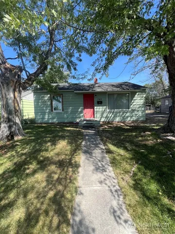 a view of a house with a yard fire pit and large tree