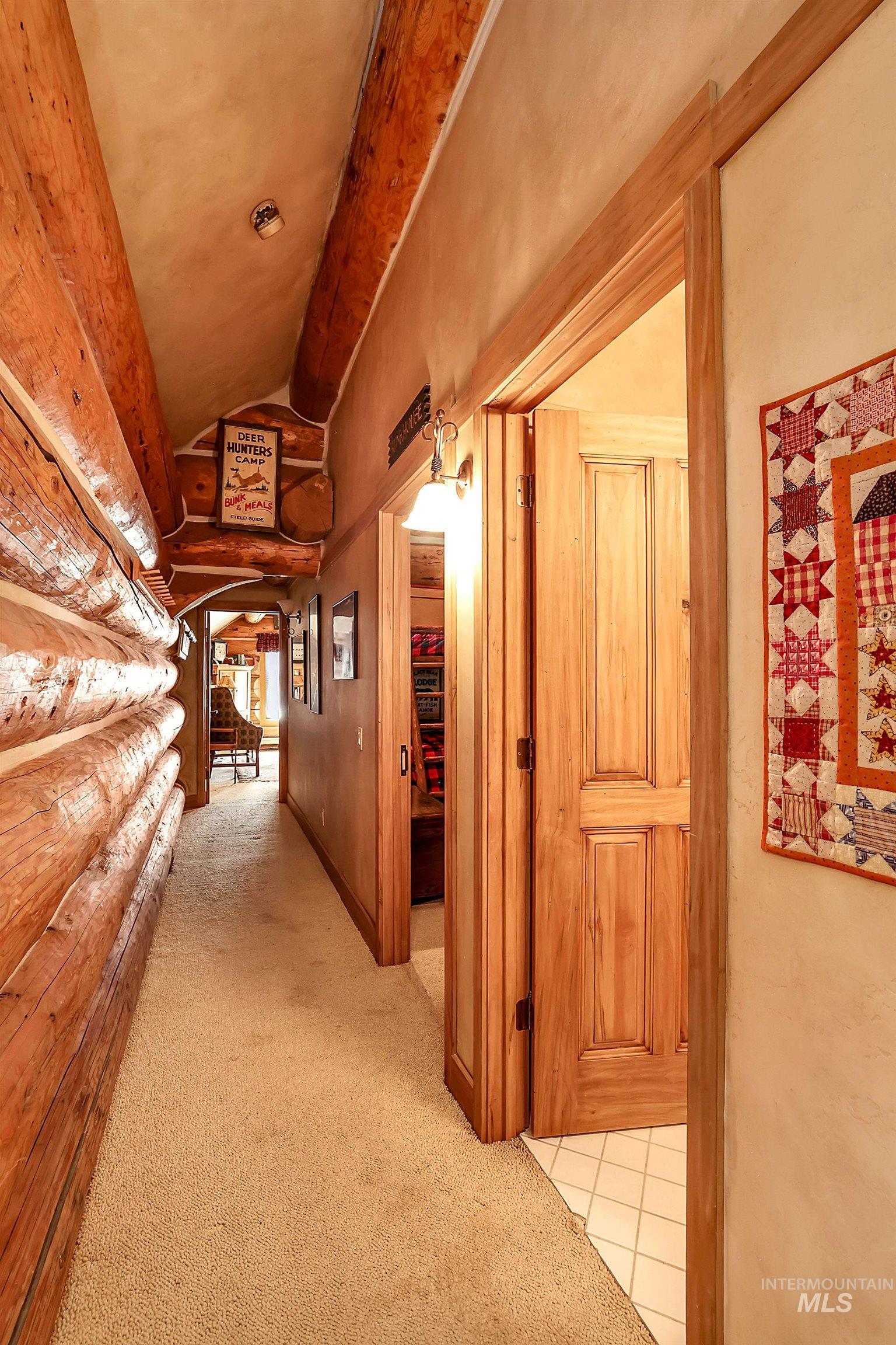 1345 Divot Lane McCall, ID 83638 - Photo 11 of 13 Hallway featuring natural log walls, wood-paneled doors, textured ceilings, and neutral carpet flooring