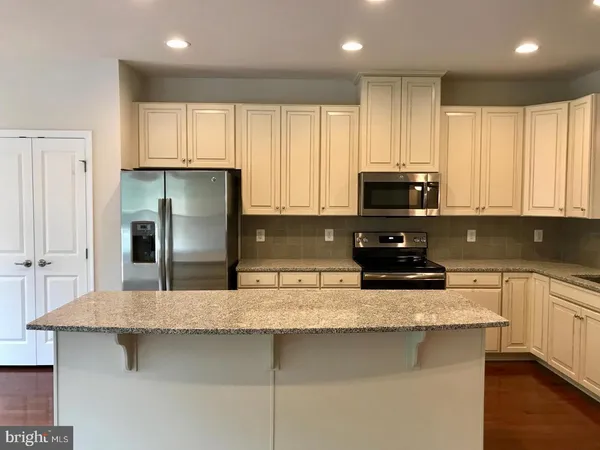 a kitchen with stainless steel appliances granite countertop a sink a stove a refrigerator a microwave and cabinets