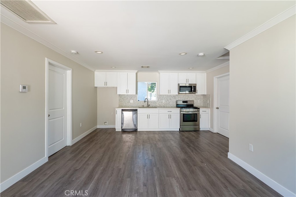 7022 Crebs Avenue Reseda, CA 91335 - Photo 4 of 20 a kitchen with wooden floors white cabinets and stainless steel appliances