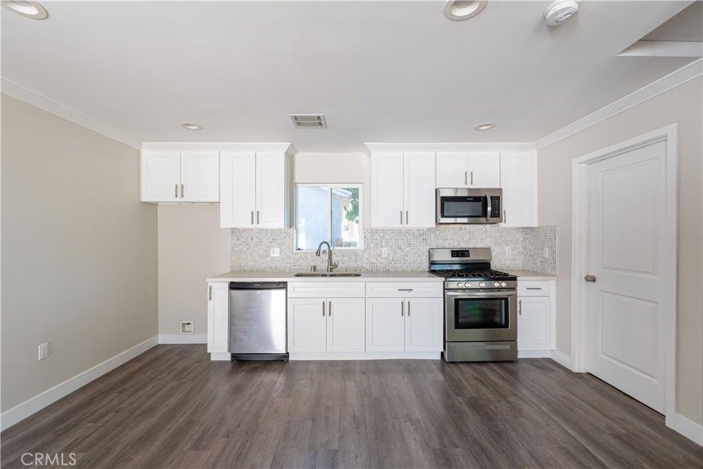7022 Crebs Avenue Reseda, CA 91335 - Photo 9 of 20 a kitchen with stainless steel appliances a sink cabinets and wooden floor